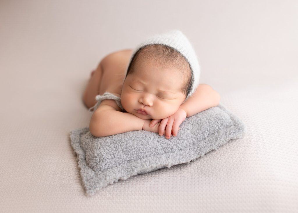 newborn baby tummy time on a grey blanket
