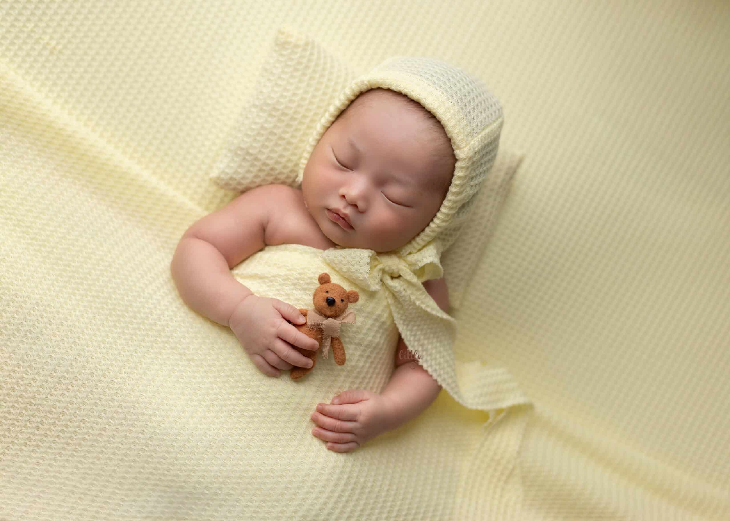 newborn baby holding a bear in his edmonton newborn photography session