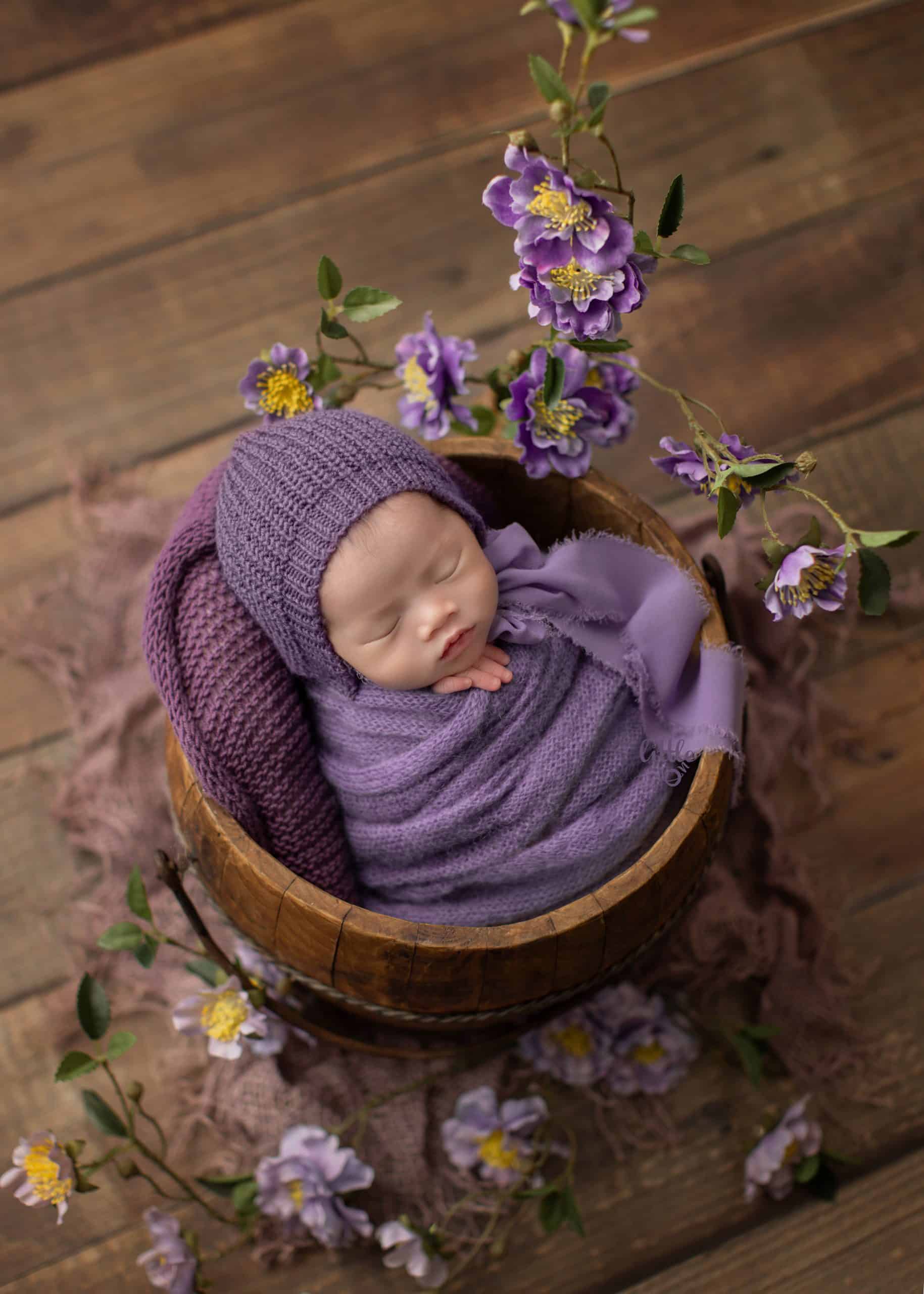 newborn baby gilr wrapped in purple with her Edmonton newborn photography set up.