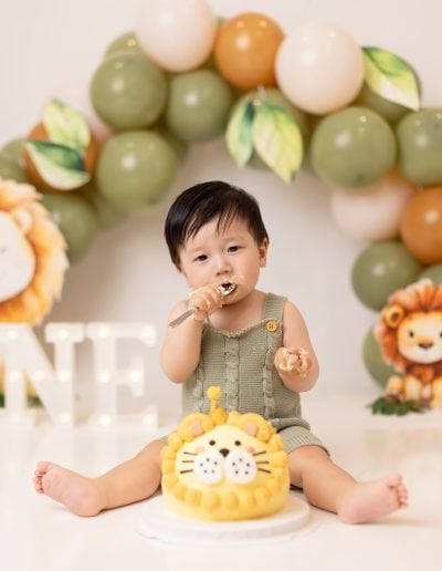 Custom lion-themed cake smash in Edmonton with green jungle decor, balloons, and a lion birthday cake.