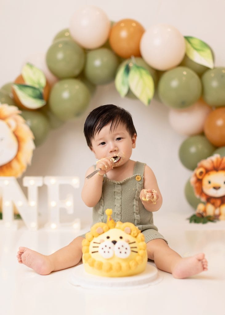 Custom lion-themed cake smash in Edmonton with green jungle decor, balloons, and a lion birthday cake.