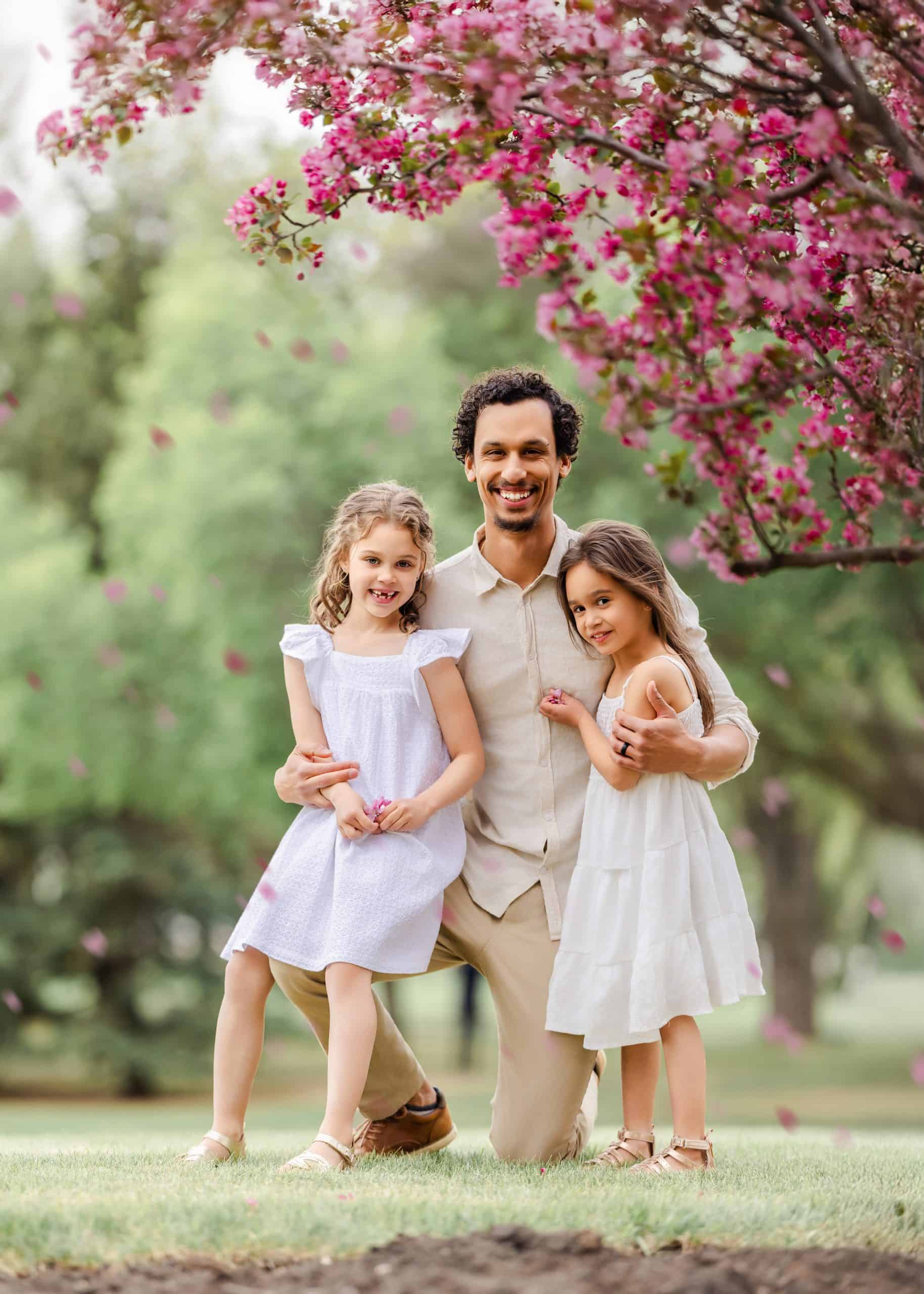 Dad hugging daughters tightly during a quiet moment in a family photoshoot in Edmonton