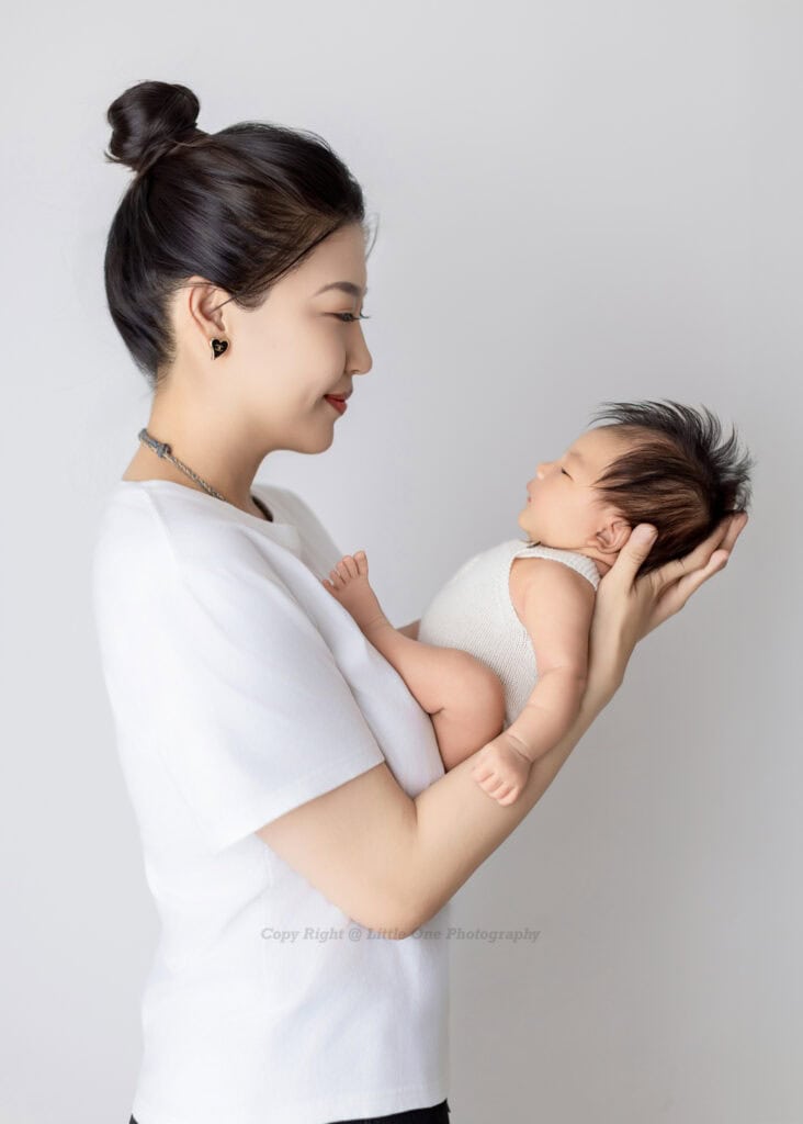 Mother holding her newborn baby in a tender, timeless studio portrait