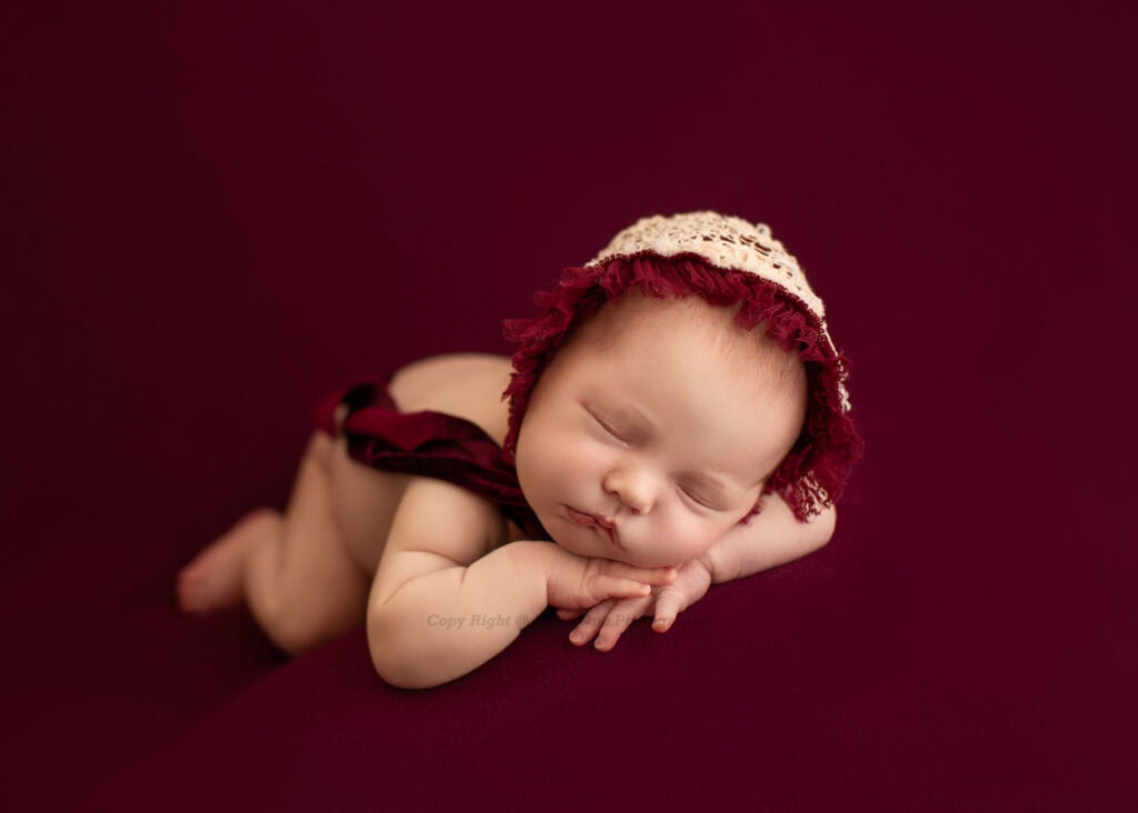 newborn photoshoot for a baby girl posed in red