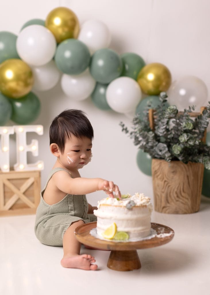 fist birthday boy putting his findger in his cake during Edmonton cake smash photo session.