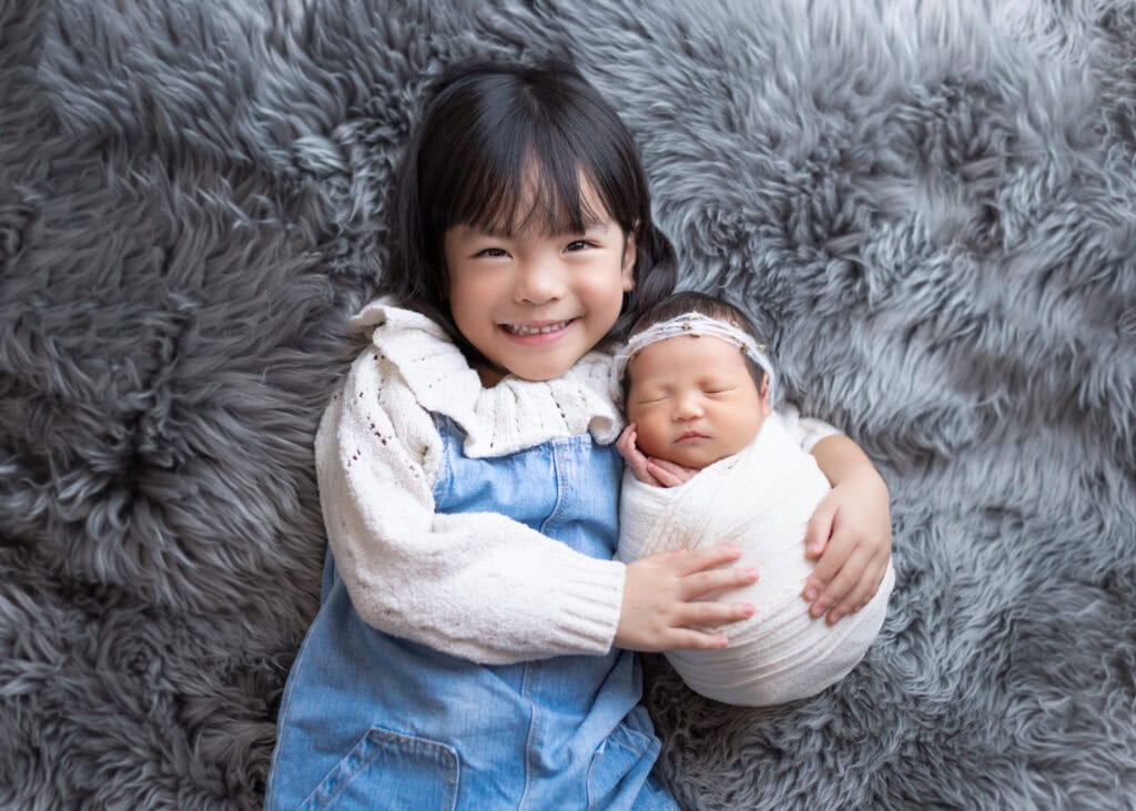 sibling sister take newborn baby for newborn photoshoot with Little One Photography
