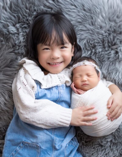 sibling sister take newborn baby for newborn photoshoot with Little One Photography
