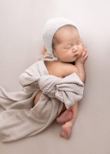 Newborn peacefully wrapped in a soft beige swaddle during a studio session in Edmonton.