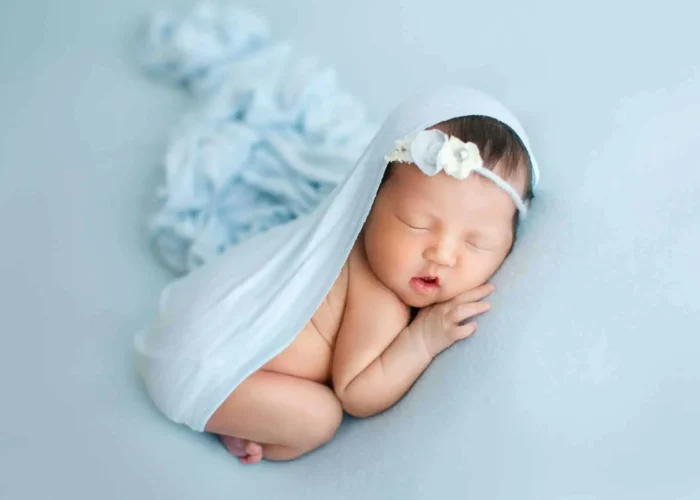 Candid newborn moment with baby’s hand reaching up near face.